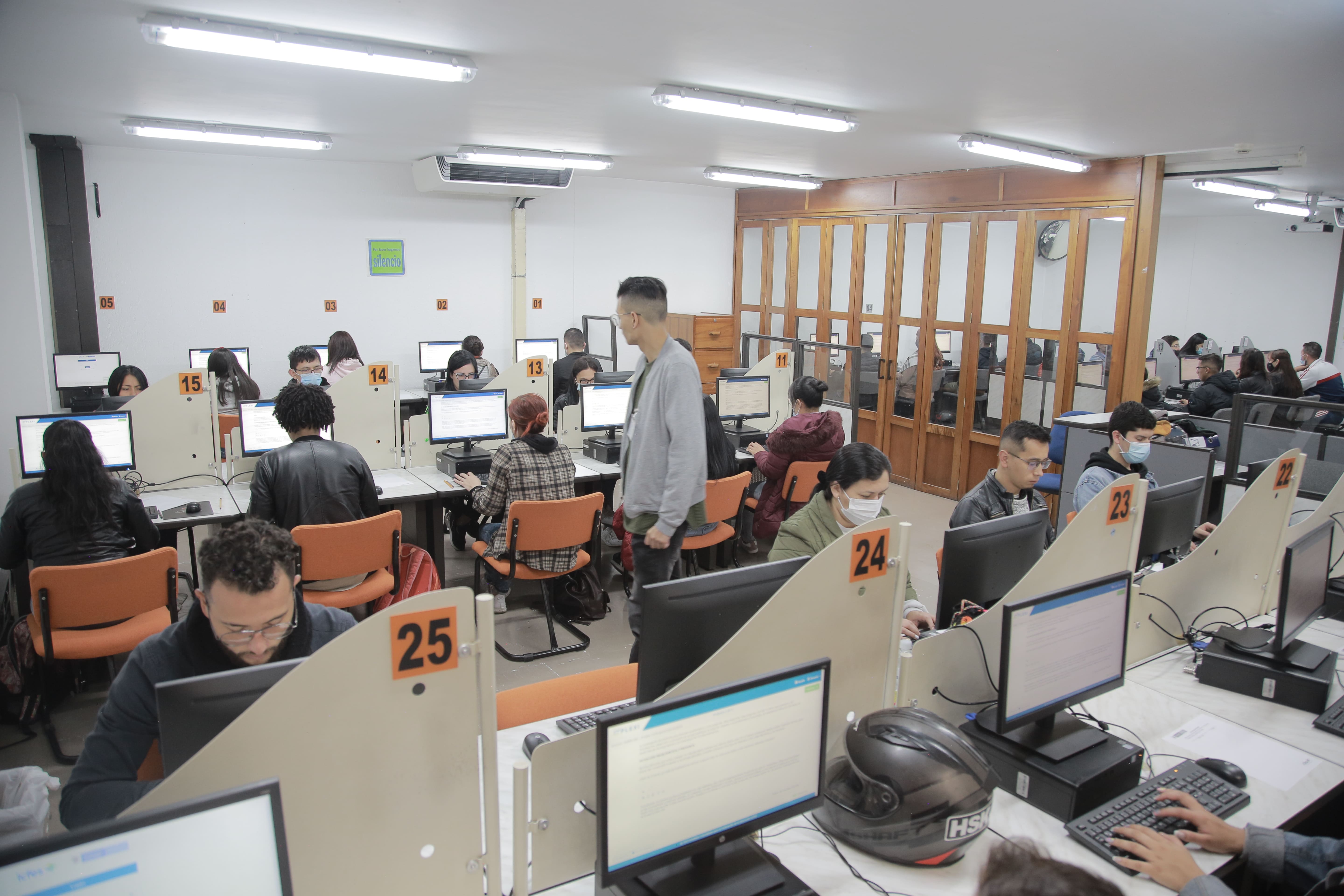 Jóvenes sentados en salón de clase cada uno con computador resolviendo una prueba electrónica.